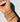 A close-up of a person's wrist adorned with multiple layered bracelets, including rainbow beaded bracelets.